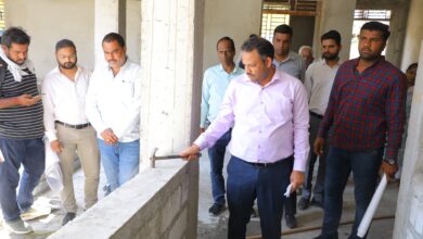 Collector Rituraj Singh inspecting ITI building construction quality with hammer in Dewas