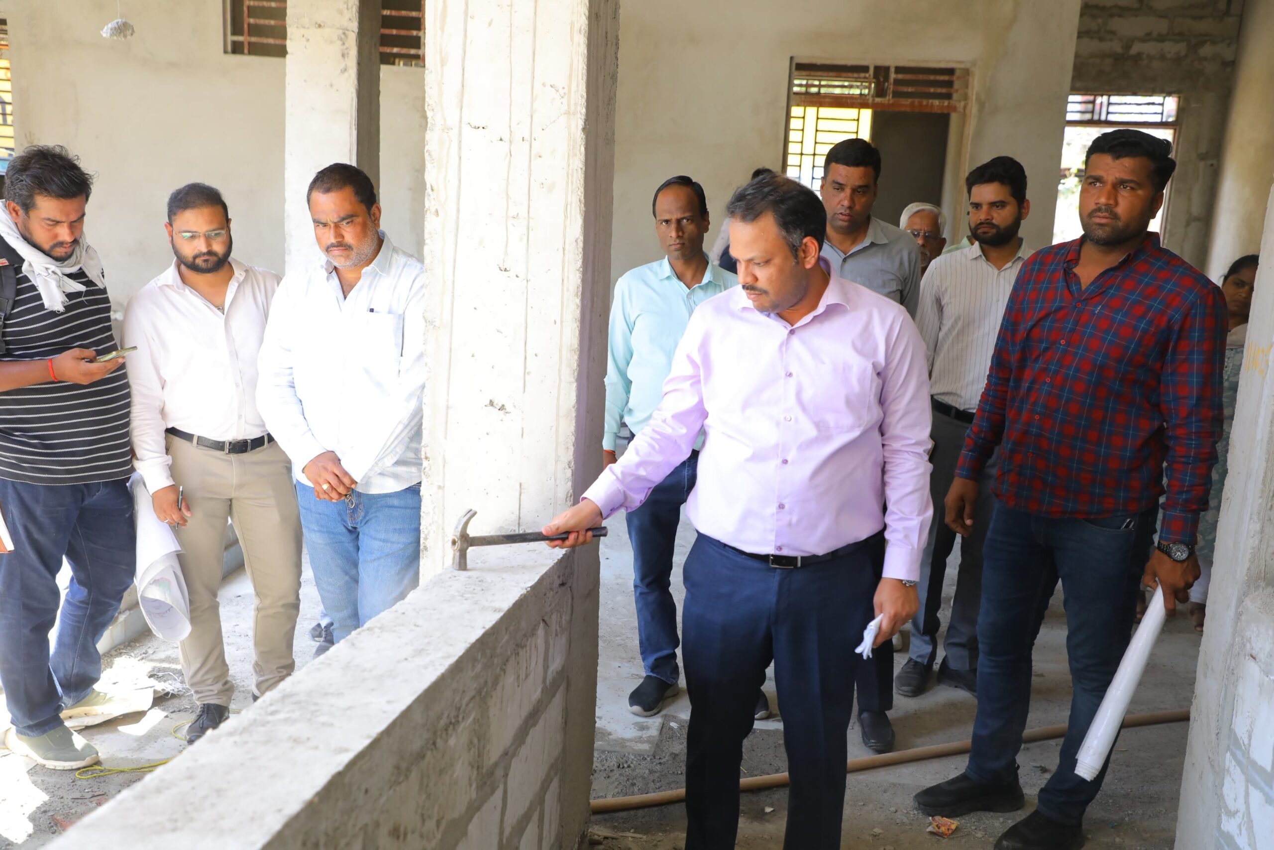 Collector Rituraj Singh inspecting ITI building construction quality with hammer in Dewas