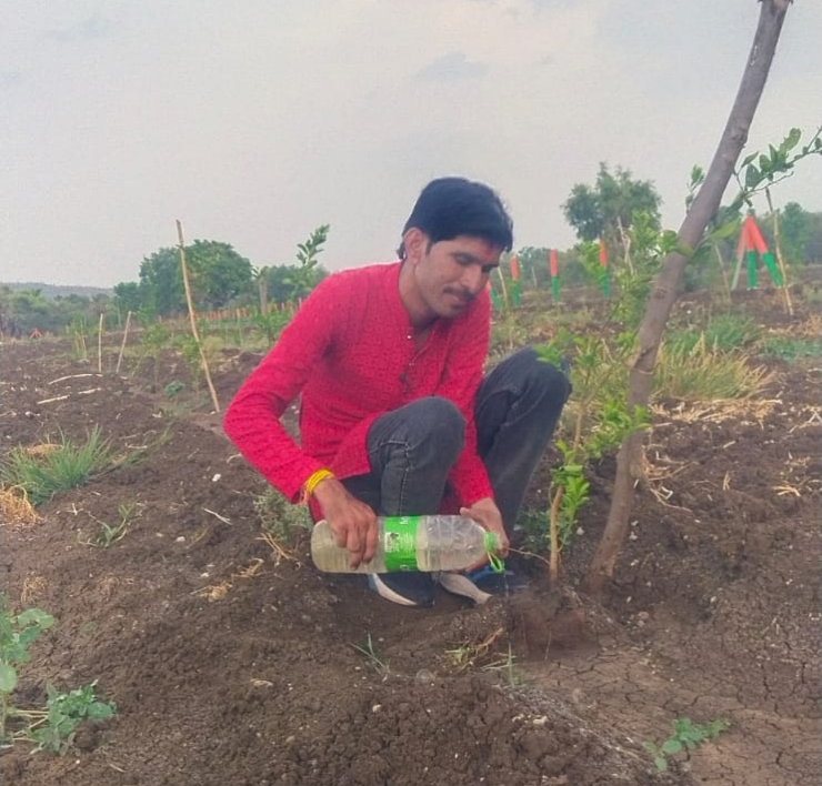 धर्मेंद्र राजपूत बोतल से पौधे में पानी डालकर उसकी देखभाल करते हुए